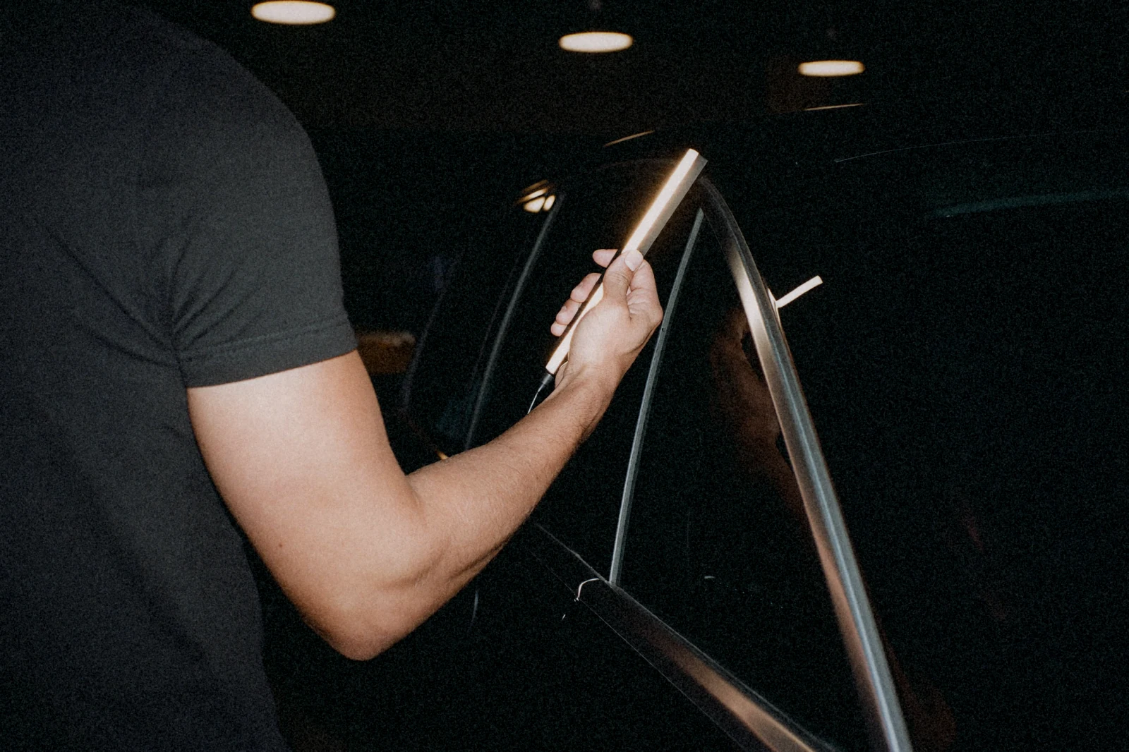Detailer inspecting glossy paint with an LED torch
